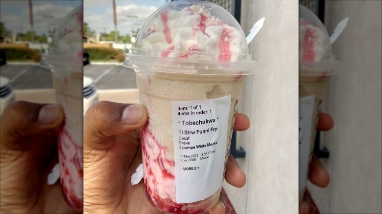 Mirrored border image of hand holding Funnel Cake Frappuccino outside in parking lot
