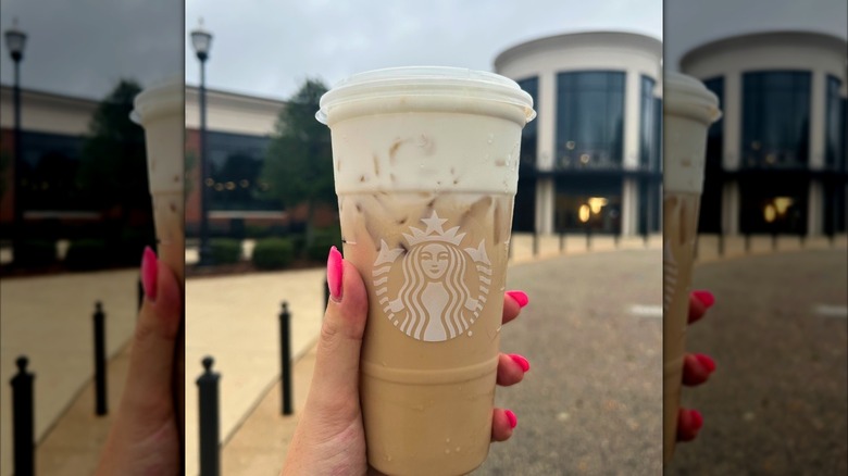 Mirrored image of hand holding Starbucks takeout cup with a protein cold foam latte outside