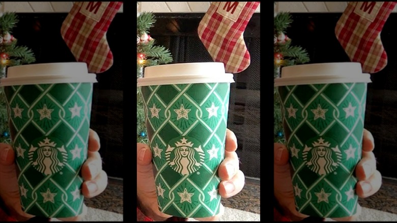 Mirrored image of hand holding festive latte cup in front of stocking