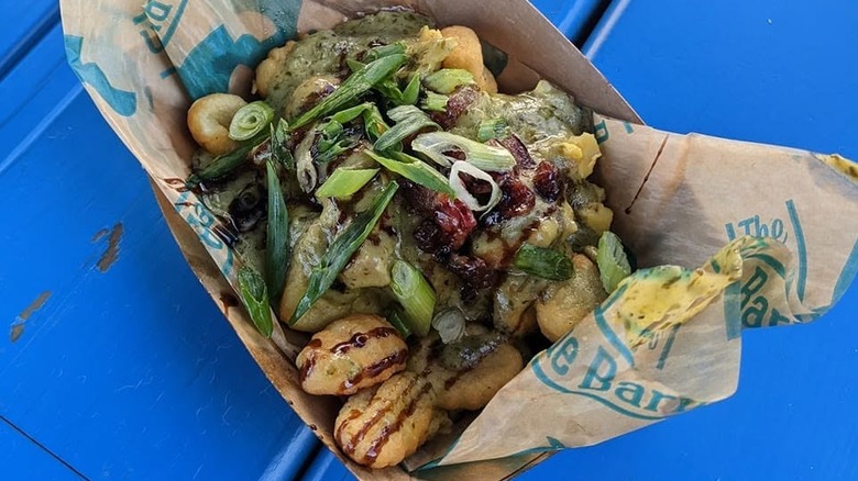 Breakfast Gnocchi in brown paper tray on blue table.