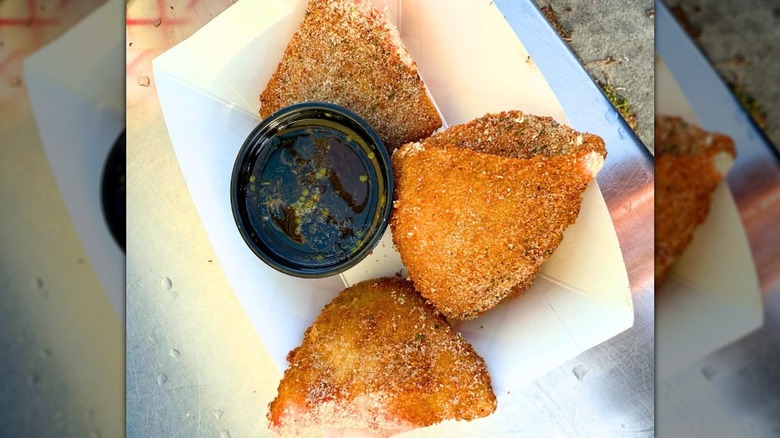 Deep-fried ranch dressing in white paper tray with sauce.