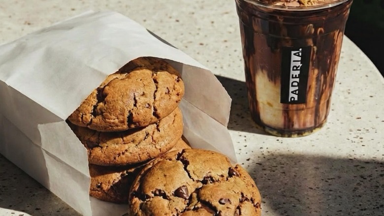 bag of chocolate chip cookies from Paderia Bakehouse with a coffee drink in the background