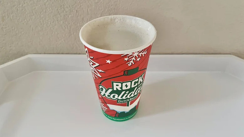 Hot chai latte in holiday cup against a beige wall