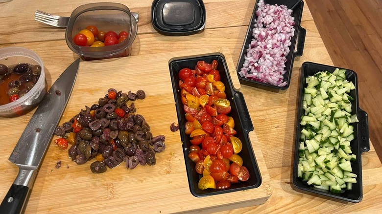 Bamboo cutting board with trays holding vegetables and knife on board