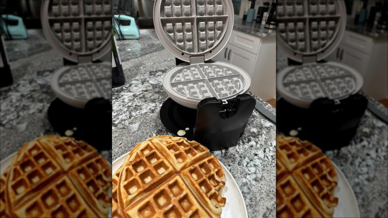 Belgian waffle maker open on countertop with a plate of Belgian waffels
