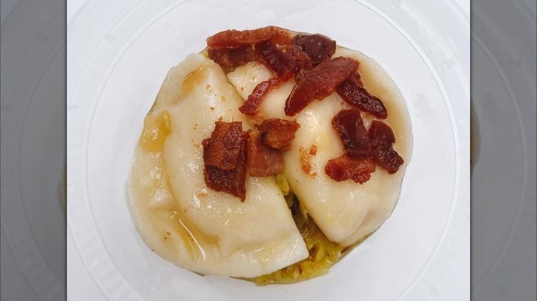 Two pierogi with bacon on white plate