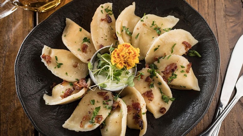 Plate of pierogi on wooden table with silverware