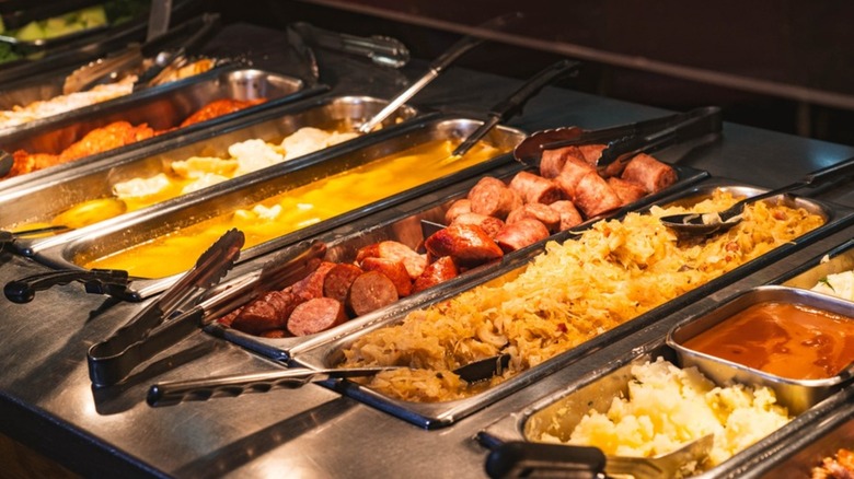 Assortment of dishes on a buffet line including sausage and sauerkraut
