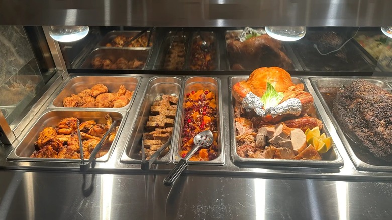 Buffet line with assortment of meats in trays including turkey
