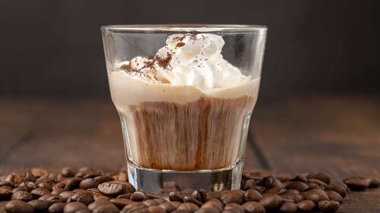 Espresso Con Panna with coffee beans scattered around the table