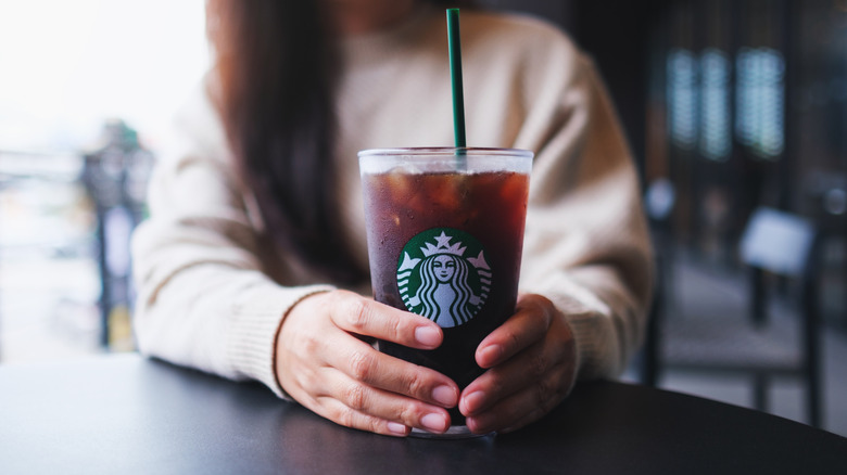 Woman holding Starbucks Iced Coffee in a tall glass