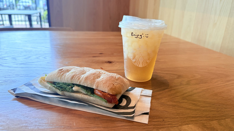Starbucks Iced Peach Green Tea Lemonade with a sandwich on a table