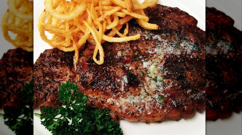 plate of ribeye from The River Palm Terrace topped with crispy fried onions and parsley