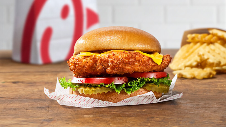 Chick-fil-A Deluxe chicken sandwich with waffle fries in background