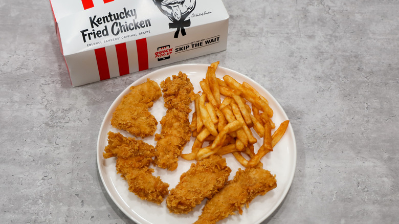 A plate with KFC Chicken Tenders and Fries next to takeout box