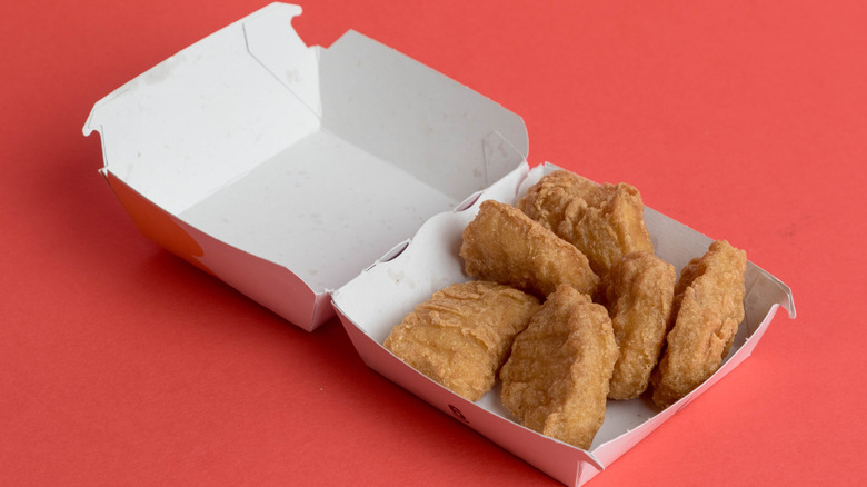 view of a McDonalds 6 Chicken McNuggets, against a red background