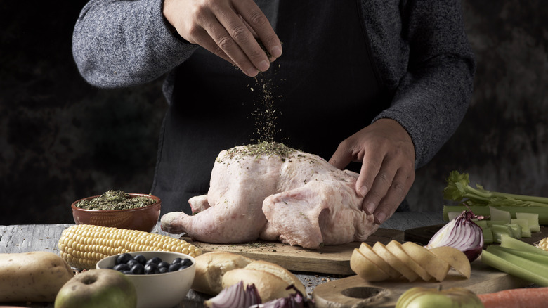Hand sprinkling seasoning onto a raw turkey