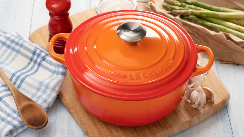 Orange Le Creuset dutch oven on wooden board