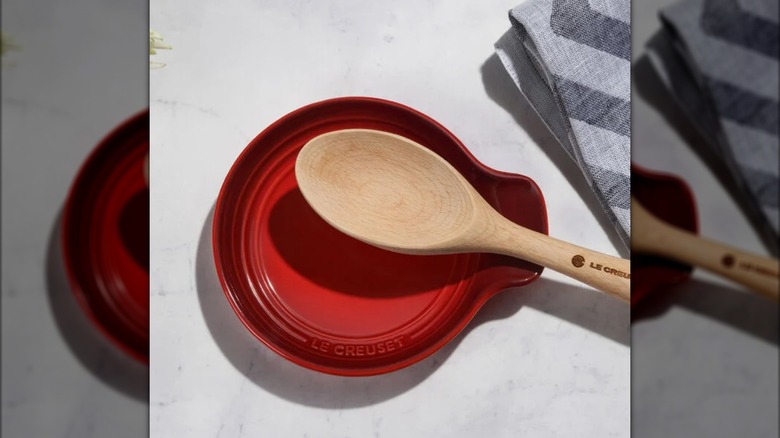 Red Le Creuset spoon rest with wooden spoon resting on top