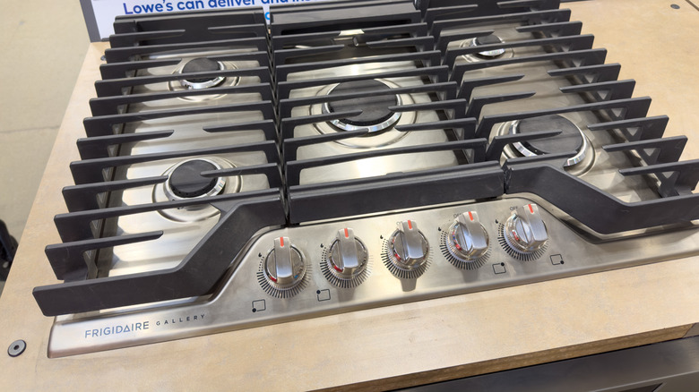 A close up of a Frigidaire stove top with a Lowe's sign partly shown in the background