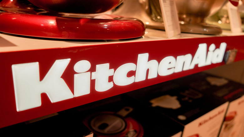 A close up of the KitchenAid logo on a shelf that seems to be holding stand mixers