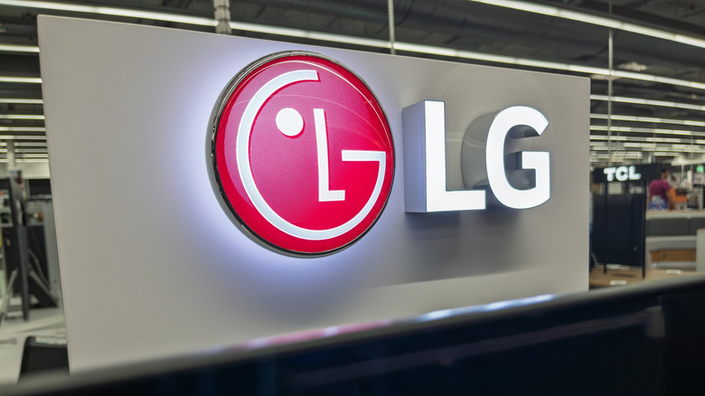 A close up of the LG logo in a giant warehouse with a TCL logo in the background