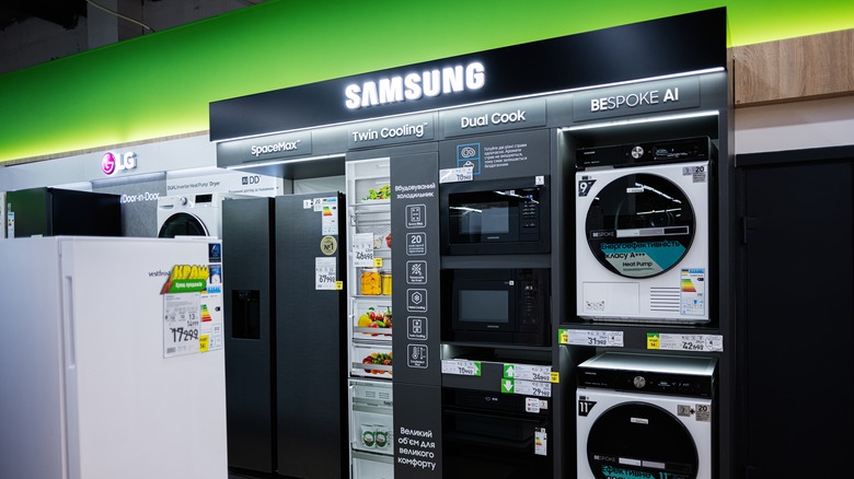 A stand showcasing Samsung home appliances including a refigerator and microwaves