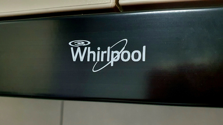 A close up of the Whirlpool logo on a black background placed on an appliance