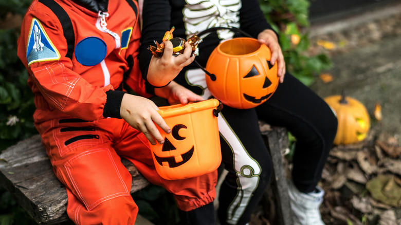 two trick-or-treaters with jack-o'-lanterns and candy