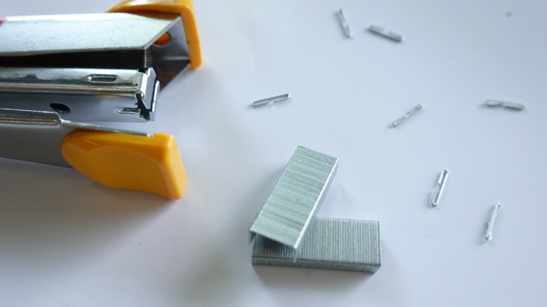 A stapler next to several staples