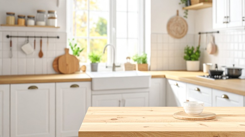A brightly-lit white kitchen with wooden countertops