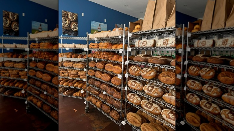 Freshly baked loaves of bread on metal shelves in bakery