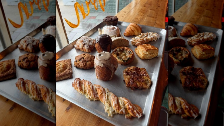 Various cakes and pastries on metal tray in bakery