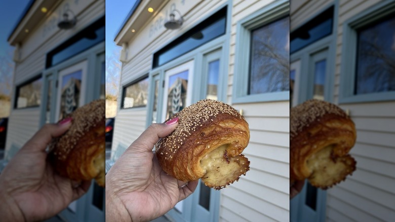 Hand holding pastry in front of bakery storefront