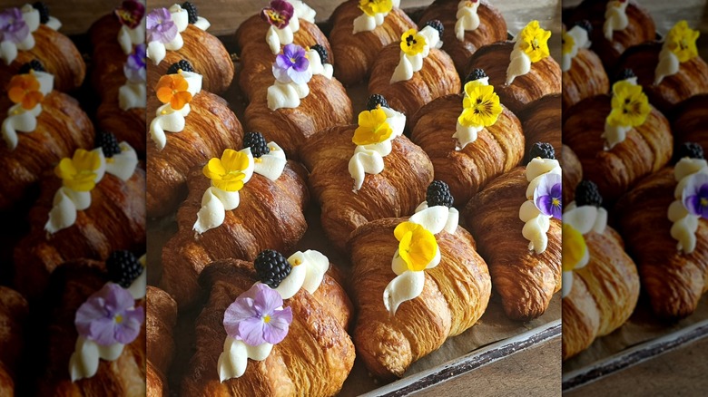 Croissants decorated with piped cream topping and edible flowers