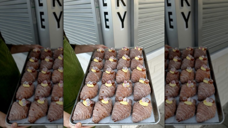 Person holding tray of decorated croissants