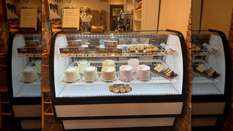 Various cakes on display on glass-fronted bakery cabinet