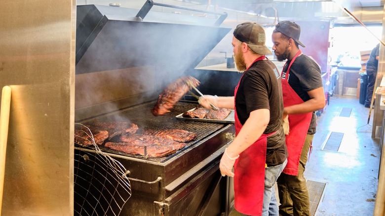 two men cooking ribs on grill