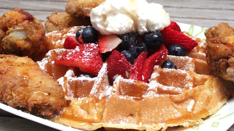 Chicken and waffles with strawberries, blueberries, and cream