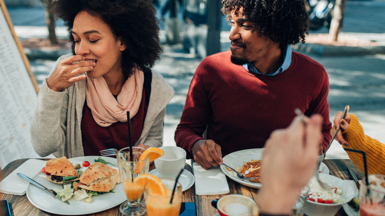 Two happy people eating brunch outside at a picnic table
