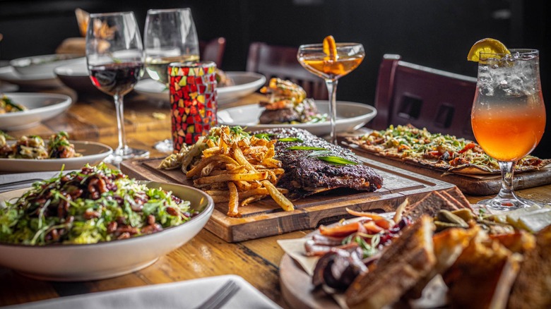 Table full of cocktails and brunch dishes, meats, potatoes, salads