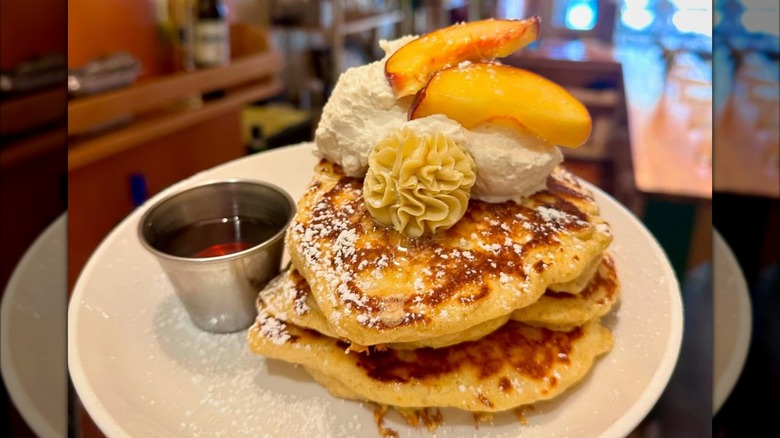 Plate of pancakes with syrup, butter, and peaches
