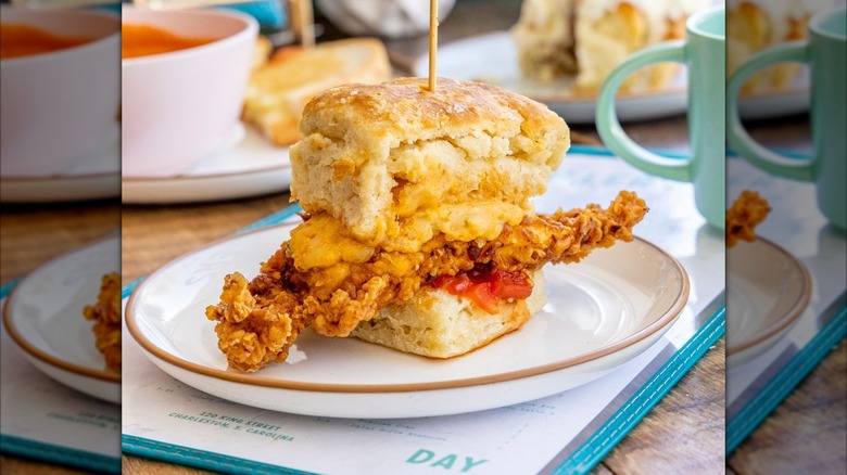 Fried chicken sandwich on a biscuit with plate sitting on a menu