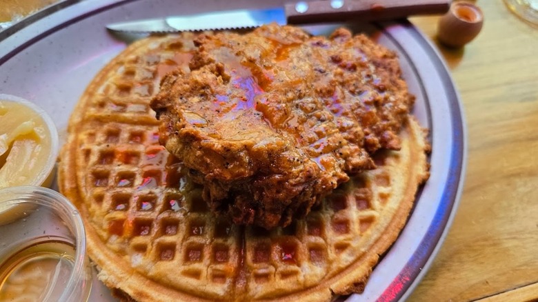 Large piece of fried chicken on waffle with syrup