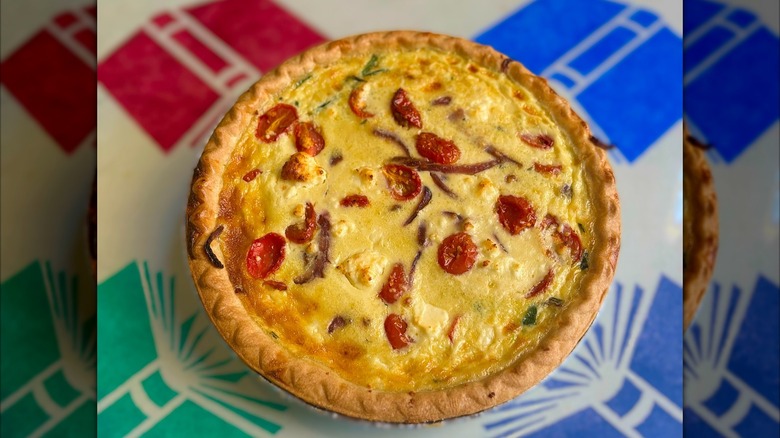 Spinach and roasted tomato quiche on a colorful table