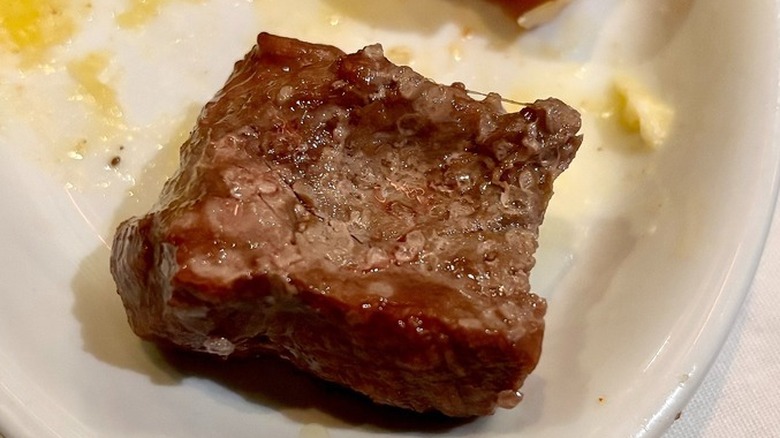 A cut up and salted piece of filet mignon on a white plate