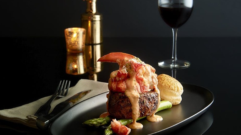 Cooked filet mignon topped with crab meat and bernaise sauce, asparagus and scallops