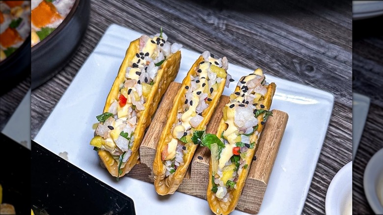 Taquitos acevichados with shrimp and mango ceviche, leche de tigre, aji mayo, wonton, and sesame