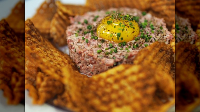 Housemade chips with beef tartar and egg yolk garnished with chives