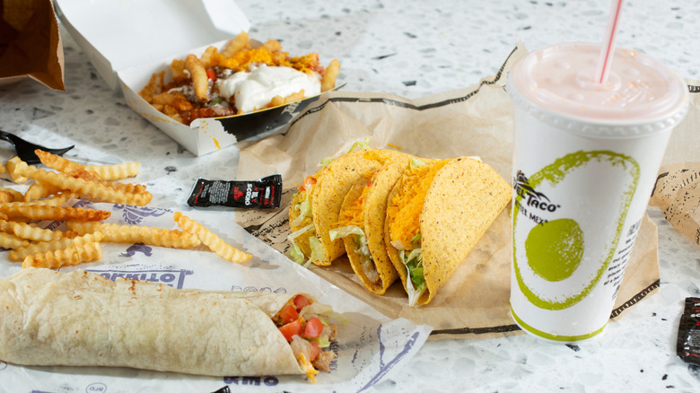 spread of Del Taco items with tacos, burrito, fries, and a drink